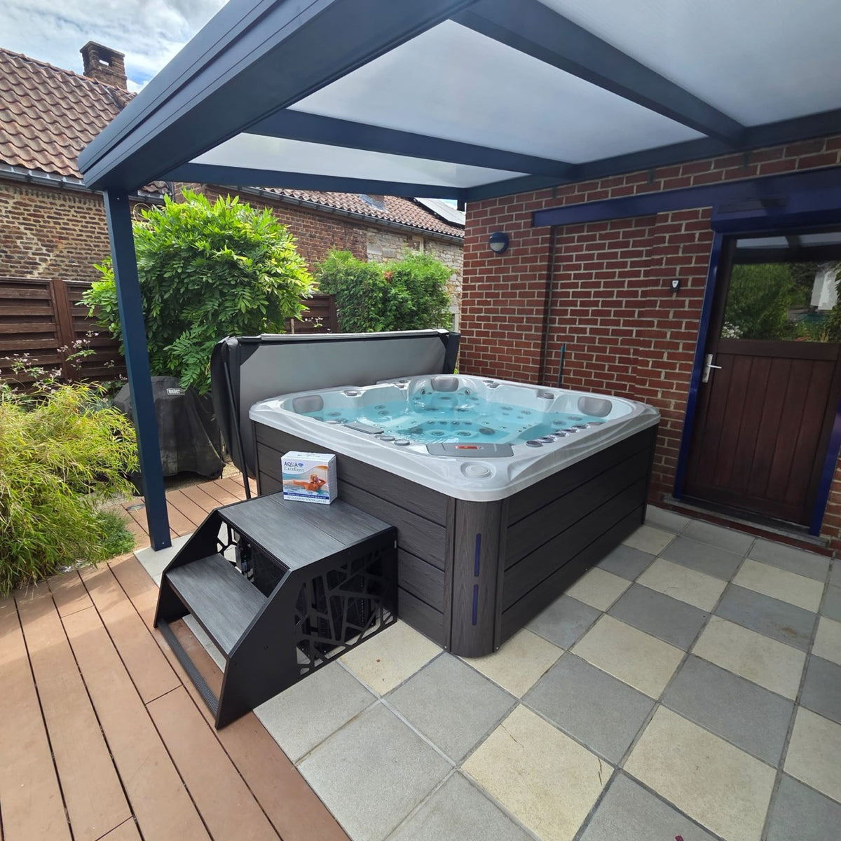 Spa installé sous une pergola avec un escalier métallique
