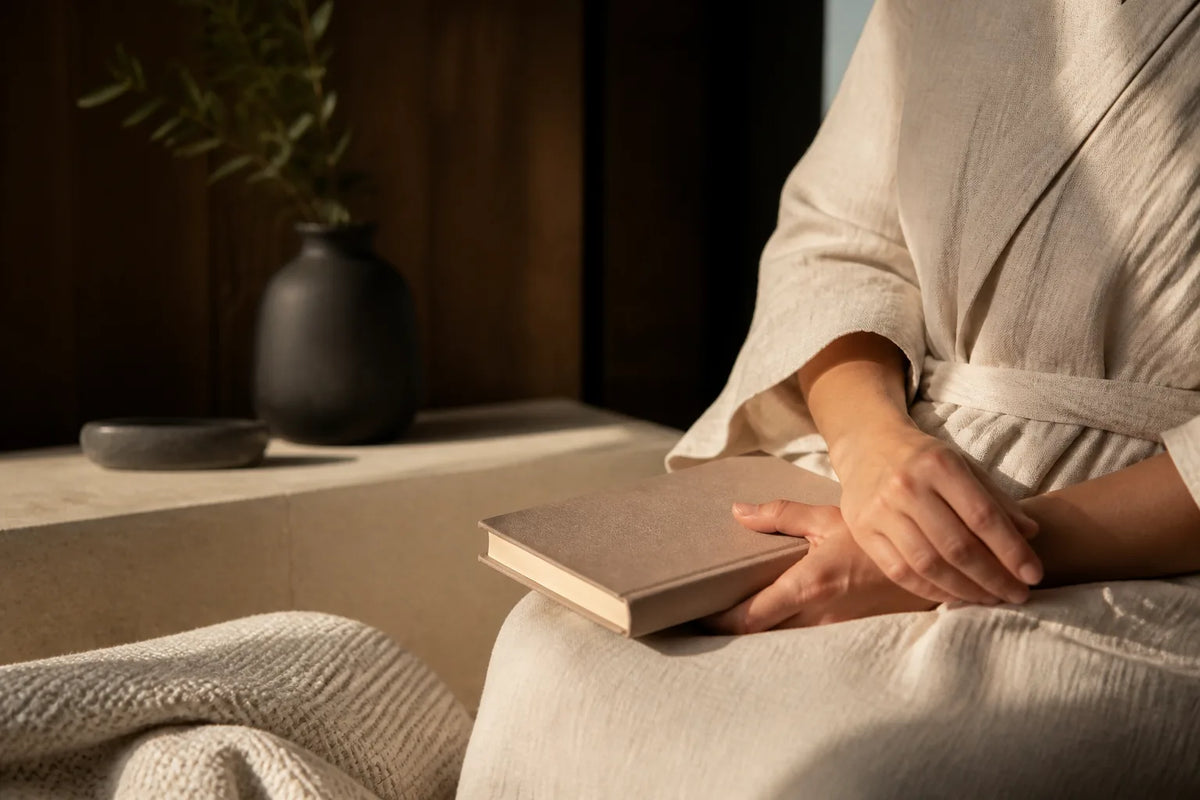 Nero 210X - sauna interior de 4-5 plazas a la luz del atardecer con un albornoz y un libro para la transición al descanso